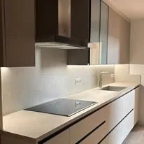 Cuina blanca amb campana d’acer i llum sota els mobles alts