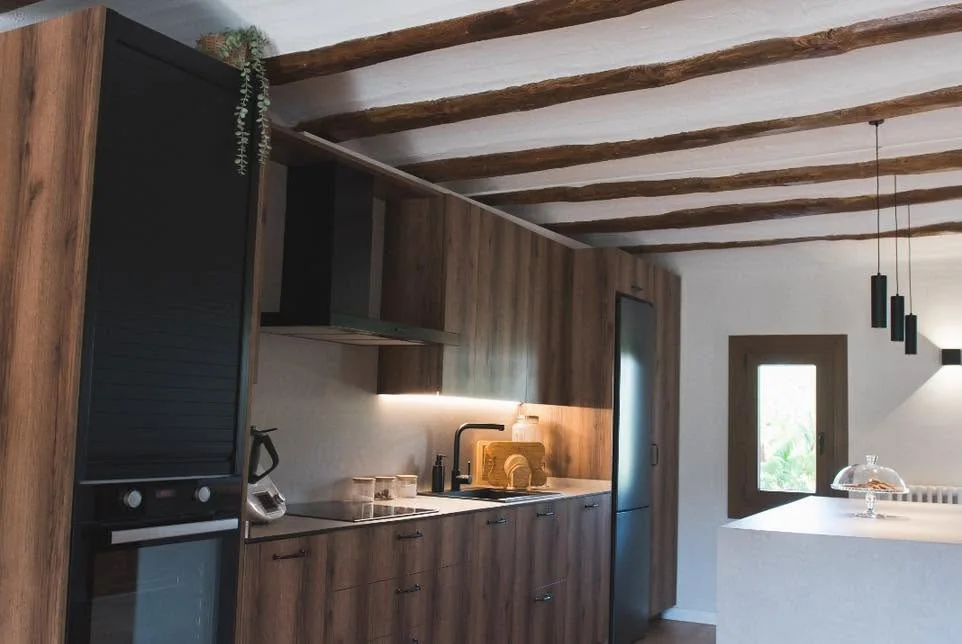 Frontal de cuina: columna amb persiana i forn, campana negra, mobles alts amb llum LED i nevera